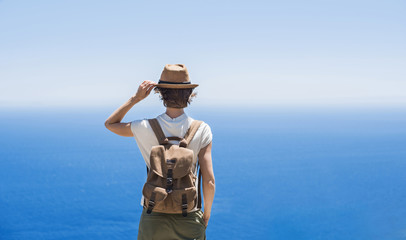 Wall Mural - Young woman traveler looking at the sea. Beautiful girl enjoying nature. Summer holidays, vacations, travel, tourism concept	