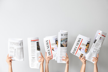 Canvas Print - Female hands with newspapers on light background