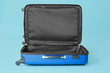 Open empty suitcase on color background
