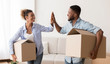 © Prostock-studio - Afro Couple Giving High-Five Carrying Moving Boxes Entering New House