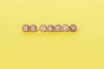 Wall Mural - Be happy text on wooden block on yellow background