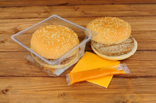 Two Microwave Beefburgers With Cheese And Sauce On A Wooden Background