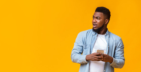 Poster - Handsome african guy with smartphone looking with interest aside