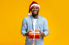 Handsome Black Guy In Red Santa Hat Holding Gift Box