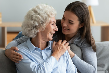 Loving young woman granddaughter hugging senior grandma giving care