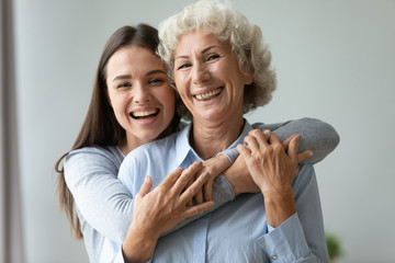 cheerful affectionate two age generation women embracing indoors, family portrait