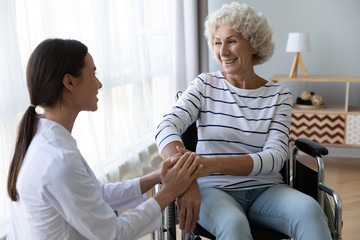 Wall Mural - Caring female nurse support disabled elder woman patient on wheelchair