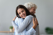Happy young granddaughter embracing hugging old retired grandmother cuddling