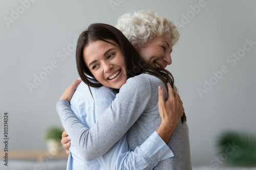 Happy young granddaughter embracing hugging old retired grandmother cuddling Poster Mural XXL