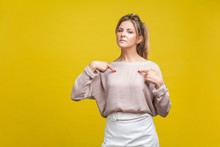This Is Me! Portrait Of Arrogant Proud Woman With Fair Hair In Casual Blouse Standing, Pointing At Herself, Boasting Personal Achievements At Camera. Indoor Studio Shot Isolated On Yellow Background