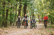 parents and kids cycling on forest trail. Young family in warm clothes cycling in autumn park. Family mountain biking on forest. Theme family active sports outdoor recreation.