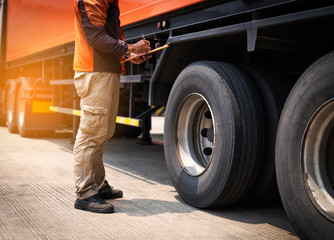 Truck Driver is Checking the Truck's Safety Maintenance Checklist. Fixing. Inspection Safety of Semi Truck Wheels Tires.	