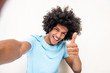 © mimagephotos - happy young North African man taking selfie against white background with thumbs up hand sign
