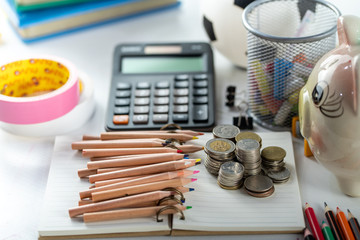 Education concept. money coin and calculator with school supplies on white table