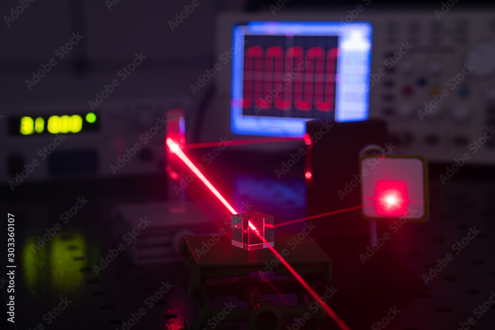 Experiment in optic lab with laser device. Red laser on optical table in physics laboratory - obrazy, fototapety, plakaty 