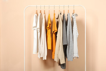 Wall Mural - fashionable clothes on hangers on a wardrobe rack on a colored background.