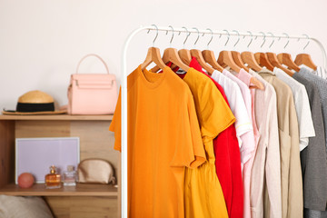 Wall Mural - Fashionable clothes on hangers on a wardrobe rack in the background of the room.
