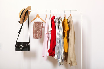 Wall Mural - Fashionable clothes on hangers on a wardrobe rack on a light background.