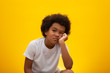 Close up ten year old boy looking to the right with bored facial expression, Isolated on yellow background