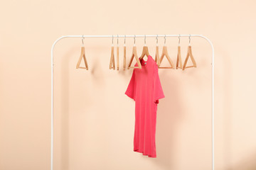 empty clothes hangers on a wardrobe rack on a colored background.