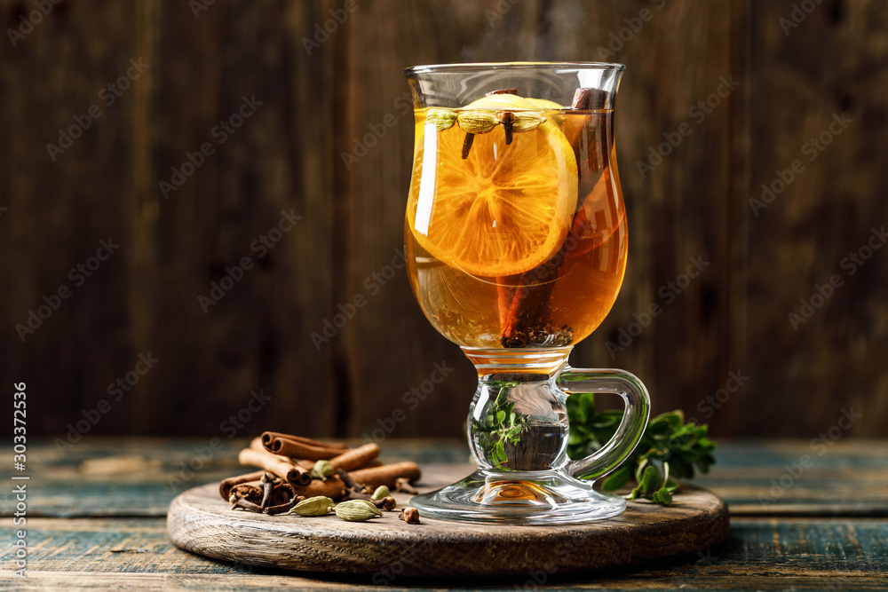 Grog. Hot drink for winter or autumn. Spicy tea and rum cocktail with lemon, cardamom, cinnamon and cloves. - obrazy, fototapety, plakaty 