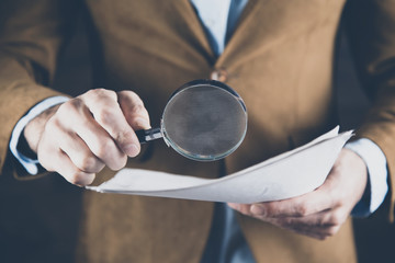 Wall Mural - man hand magnifier with document on dark background