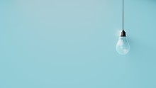 Singular Hanging Light Bulb On Bright Blue Background With Space For Text
