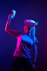 Woman is using virtual reality headset. Neon light studio portrait.