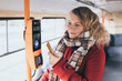 Young blonde woman making payment of public transport ticket fare at automatic contactless machine with a card