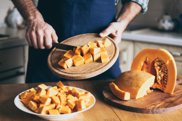 Man cuts pumpkin in the kitchen