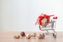 Gift Box On Miniature Shopping Cart On White Background. Christmas And Happy New Year Concept.