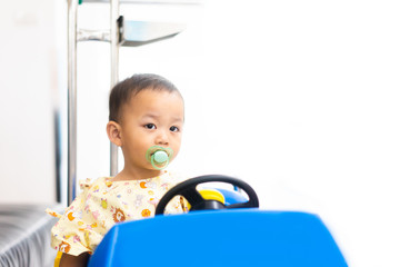 Poster - Sick child baby boy driving toy car with a fever at hospital