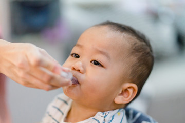 Wall Mural - Little baby boy un accept to drink medicine syrup with syringe.