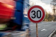 A Fast Driving Blue Speeding Truck With Motion Blur Effect Near The Traffic Sign Limiting The Maximum Speed To 30 Kph