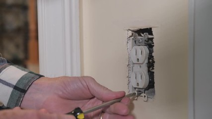 Wall Mural - Male electrician repairing residential electrical wall power outlet. 