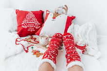 Woman In Socks On White Christmas Background With Cups Of Cocoa Drink And  Christmas Presents. Cozy Winter Holidays