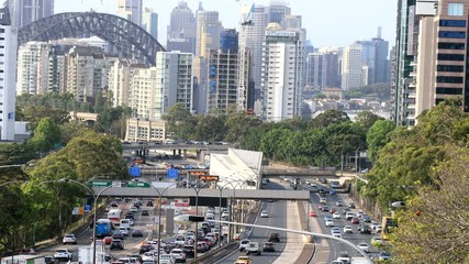 Poster - Steel arch of the Sydney harbour bridge over high-rise office towers and Warringah freeway commute traffic in morning rush hour.