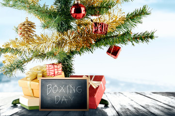 Wall Mural - Christmas tree with gift box and Boxing Day text on the blackboard on wooden floor