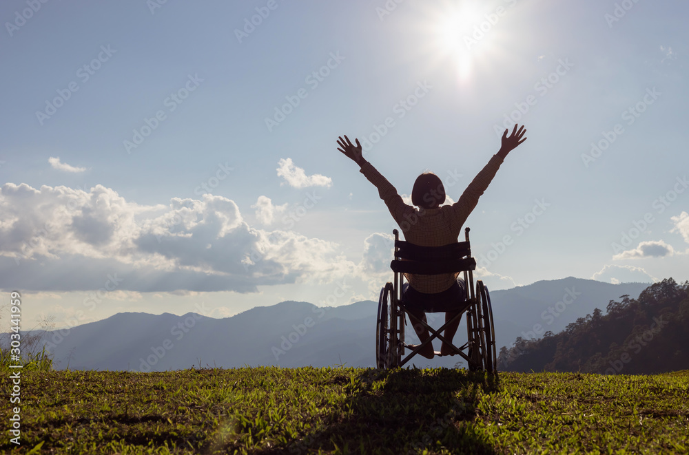 Happy disabled child in a wheelchair and stretching hands at sunset. back view, - obrazy, fototapety, plakaty 