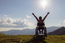 Happy Disabled Child In A Wheelchair And Stretching Hands At Sunset. Back View,