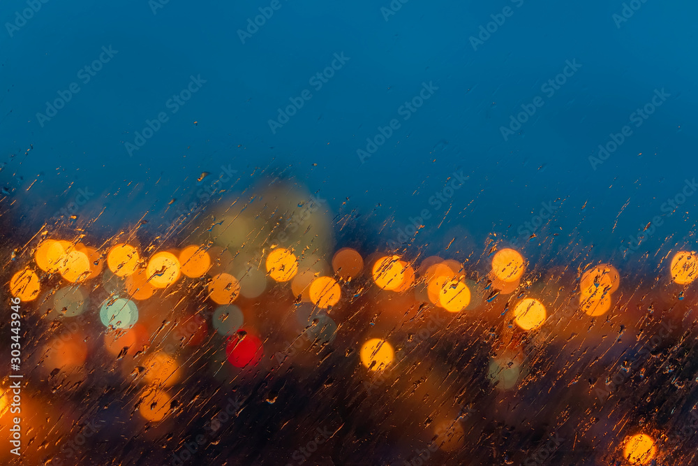 Abstract blurred picturesque background. Night defocused view of the city lights through the window with raindrops - obrazy, fototapety, plakaty 