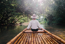 Traveling By Thailand. Back View Of Tourist Enjoying View Sailing Jungle River On Traditional Bamboo Raft.