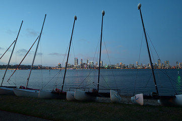 Wall Mural - Catamaran sailing boats against Perth central business district skyline at sunset