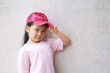 © kornnphoto - Asian child cute or kid girl smiling and happy with sport dancer and hand on hat with wear pink shirt for beauty fashion on summer holiday travel or party and loft gray cement wall background