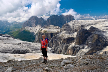 Canvas Print - Smiling woman trekker in sport clothes with backpack feeling happy on her vacation in Italian Alps. Passo Pordoi. Piz Boe summit. Dolomites. Italy.