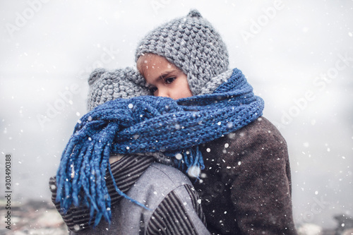 Cuadros en Lienzo Girl in knitted grey hat hugging her frozen smaller brother