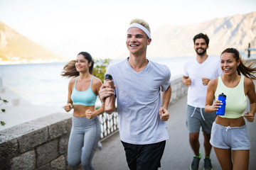 Canvas Print - Happy fit people running and jogging together in summer sunny nature