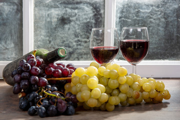 Composition with two wineglasses, grapes and bottles of red wine