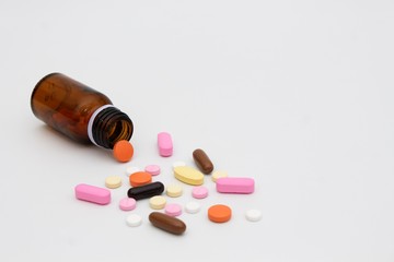 Colorful and various pills come out from glass bottle