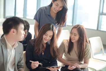 Business meeting and teamwork concept. Group of Asian colleagues discussing about project data report using digital tablet in conference room. Coworkers team sharing productive ideas in modern office.